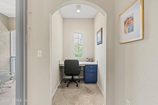 10075 N Gate Pkwy Unit 614, Jacksonville, FL 32246 - home office featuring baseboards, arched walkways, built in desk, a textured wall, and light carpet