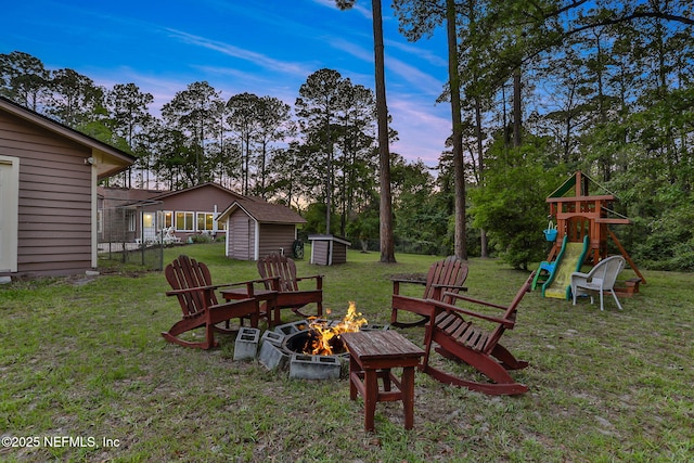 4864 County Road 218, Middleburg, FL 32068 - yard at dusk featuring a storage shed, a playground, a fire pit, and an outbuilding