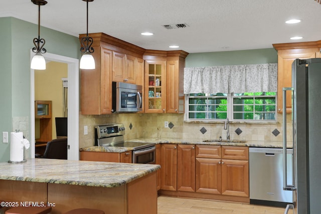 4864 County Road 218, Middleburg, FL 32068 - kitchen with light stone counters, glass insert cabinets, visible vents, appliances with stainless steel finishes, and a sink