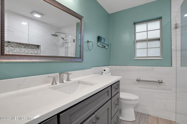 4864 County Road 218, Middleburg, FL 32068 - full bathroom with a tile shower, vanity, a wainscoted wall, toilet, and tile walls