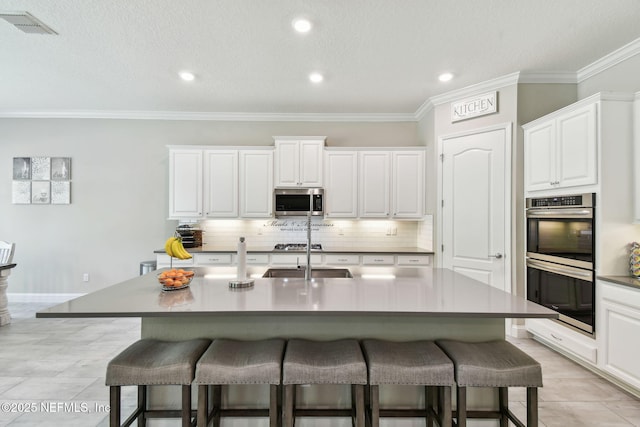 kitchen with decorative backsplash, a breakfast bar, a sink, and appliances with stainless steel finishes