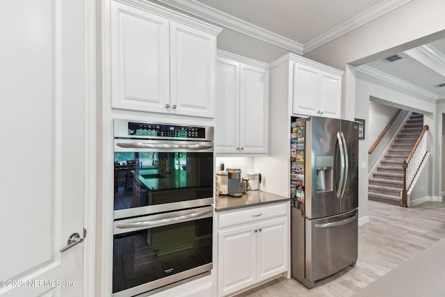 kitchen featuring crown molding, white cabinets, visible vents, stainless steel appliances, and decorative backsplash