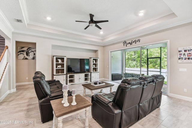 living room featuring a tray ceiling, crown molding, ceiling fan, and visible vents