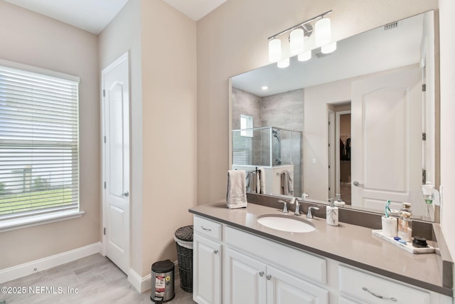 bathroom with a closet, vanity, visible vents, a stall shower, and baseboards