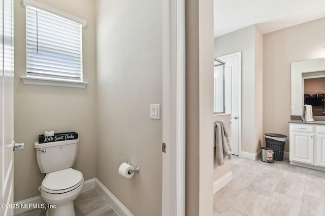 bathroom with toilet, vanity, and baseboards