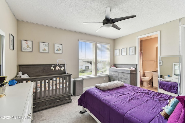 carpeted bedroom featuring a ceiling fan, ensuite bath, and a textured ceiling