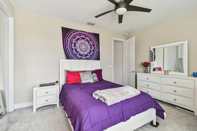 bedroom with visible vents, baseboards, light colored carpet, and a textured ceiling