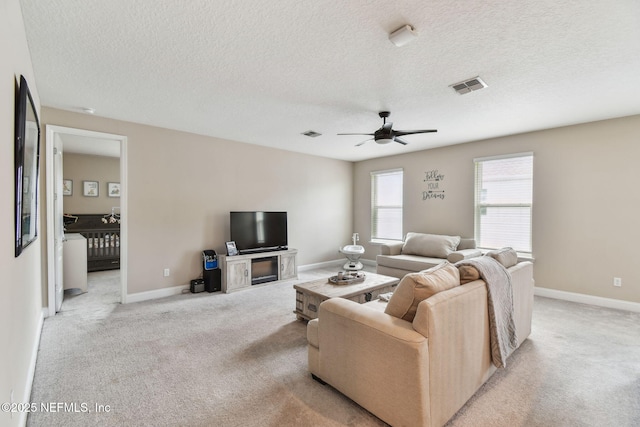 living area featuring light carpet, baseboards, a ceiling fan, and visible vents