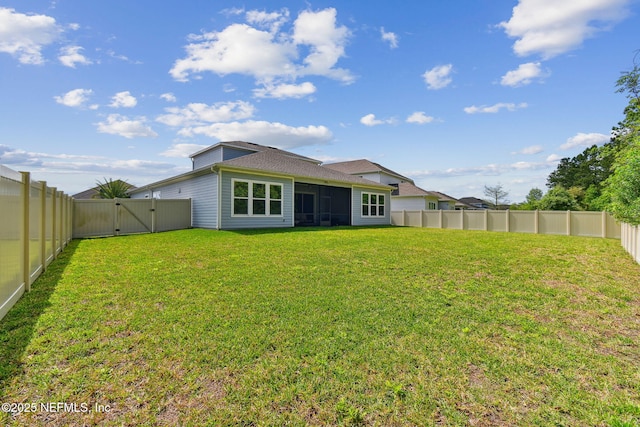 rear view of house with a sunroom, a yard, a fenced backyard, and a gate