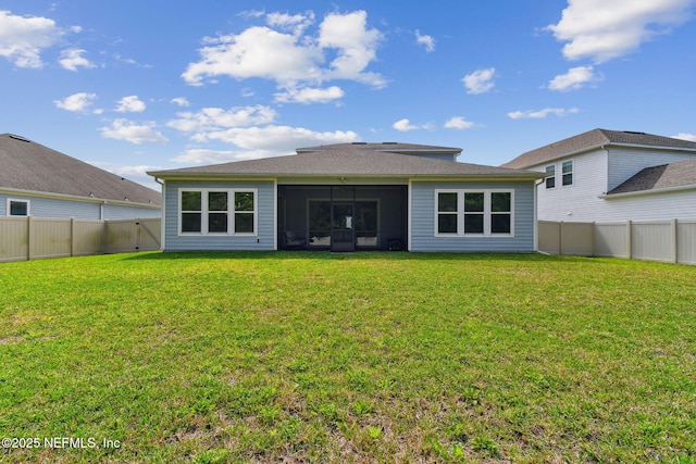 rear view of house with a sunroom, a yard, and a fenced backyard