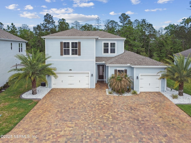 traditional-style home featuring decorative driveway and roof with shingles