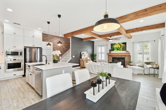 258 Haas Ave, Saint Augustine, FL 32095 - dining space featuring ceiling fan, light wood-style floors, a glass covered fireplace, beamed ceiling, and stairs