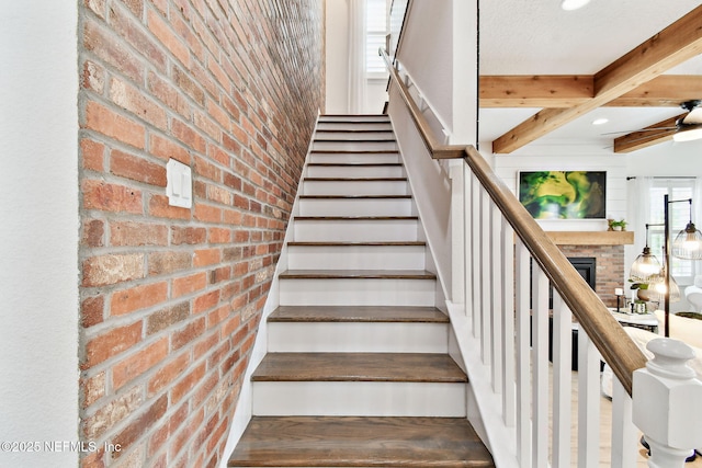 258 Haas Ave, Saint Augustine, FL 32095 - stairway featuring brick wall, a fireplace, wood finished floors, ceiling fan, and beam ceiling