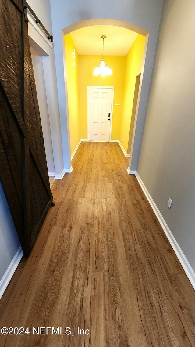 11775 Blueberry Ln, Macclenny, FL 32063 - corridor featuring arched walkways, a barn door, a chandelier, wood finished floors, and baseboards