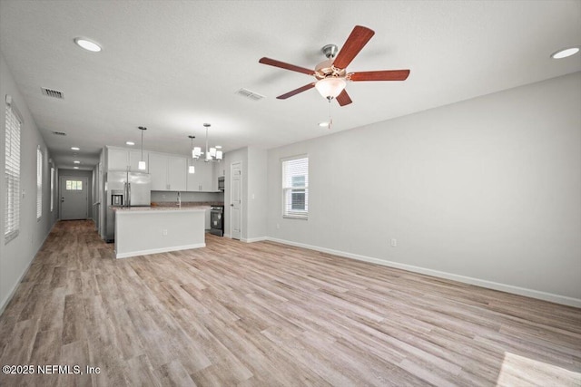 8922 Free Ave, Jacksonville, FL 32211 - unfurnished living room with ceiling fan with notable chandelier, light wood finished floors, baseboards, and visible vents