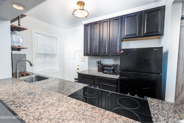 kitchen featuring crown molding, dark cabinets, tasteful backsplash, black appliances, and a sink