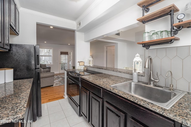 kitchen featuring light tile patterned floors, crown molding, black appliances, decorative backsplash, and a sink
