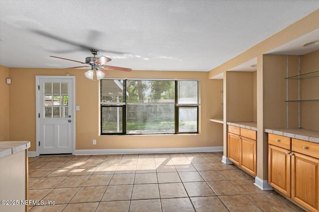 4263 Springwood Rd, Jacksonville, FL 32207 - kitchen with baseboards, tile counters, light tile patterned floors, a textured ceiling, and a ceiling fan