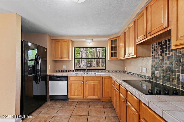 4263 Springwood Rd, Jacksonville, FL 32207 - kitchen with glass insert cabinets, black appliances, a sink, decorative backsplash, and tile counters
