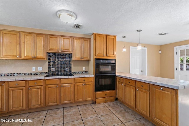 4263 Springwood Rd, Jacksonville, FL 32207 - kitchen featuring a peninsula, visible vents, tile counters, and black appliances