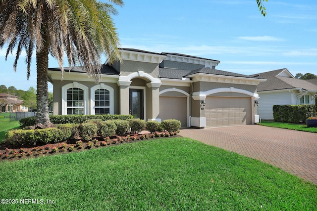 mediterranean / spanish house with a front yard, stucco siding, decorative driveway, and an attached garage