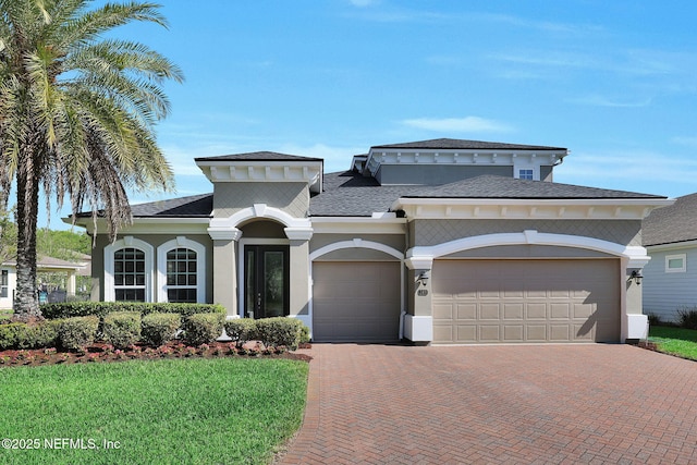 mediterranean / spanish home featuring a shingled roof, decorative driveway, a garage, and stucco siding