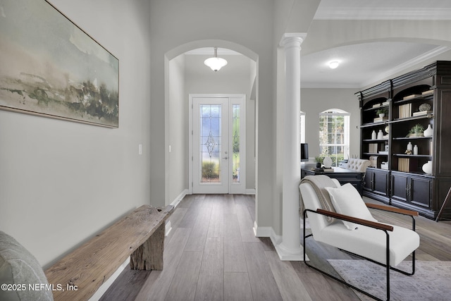 foyer entrance featuring arched walkways, a healthy amount of sunlight, wood finished floors, and crown molding