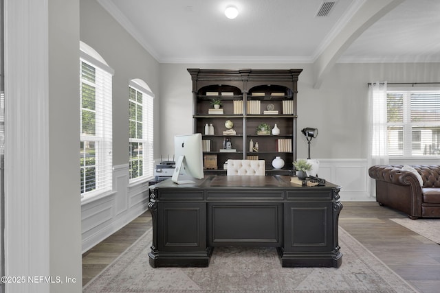 home office featuring crown molding, wood finished floors, visible vents, and a wainscoted wall