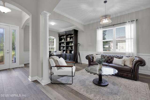 living room with arched walkways, a wainscoted wall, and a healthy amount of sunlight