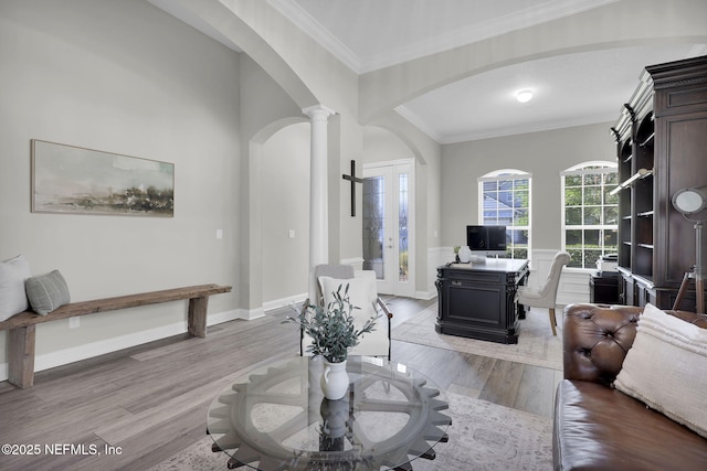 living area featuring decorative columns, arched walkways, light wood-type flooring, and crown molding