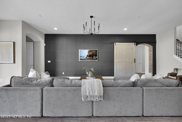 living room featuring recessed lighting, arched walkways, wood finished floors, and a textured ceiling