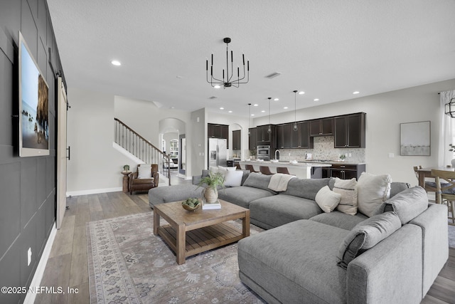 living area featuring recessed lighting, a textured ceiling, light wood-style floors, visible vents, and arched walkways