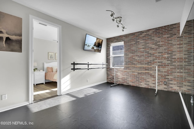 unfurnished room with brick wall, baseboards, and visible vents