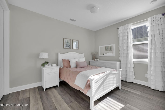 bedroom with wood finished floors, baseboards, and visible vents