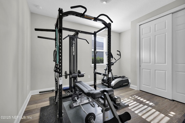 exercise area with baseboards and wood finished floors