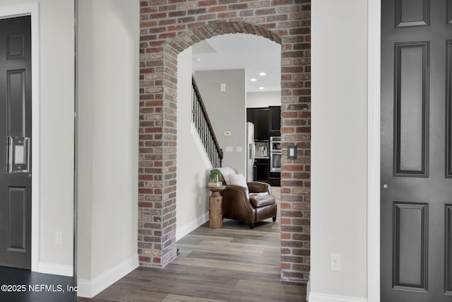 hallway with baseboards, arched walkways, recessed lighting, wood finished floors, and stairs