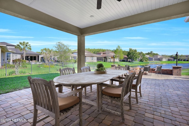 view of patio with a residential view, a ceiling fan, outdoor dining area, a water view, and fence
