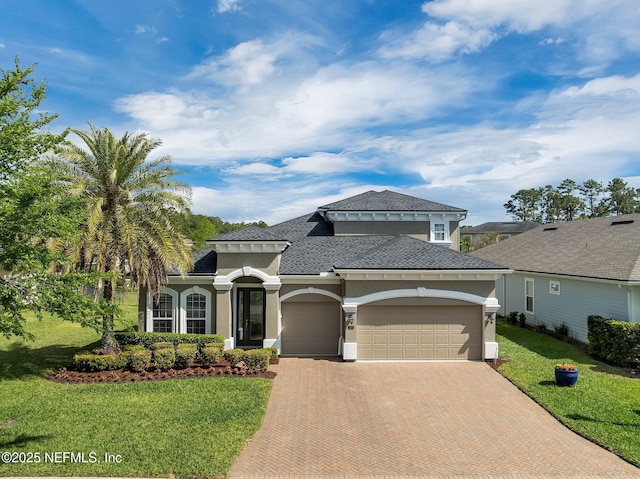 mediterranean / spanish home with a front yard, a garage, decorative driveway, and stucco siding