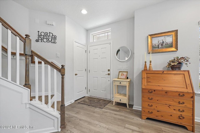 foyer featuring recessed lighting, stairs, light wood finished floors, and baseboards