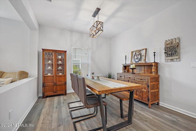 dining room with a notable chandelier, baseboards, and wood finished floors