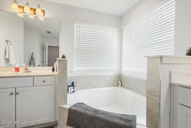 bathroom with visible vents, a garden tub, vanity, and a healthy amount of sunlight