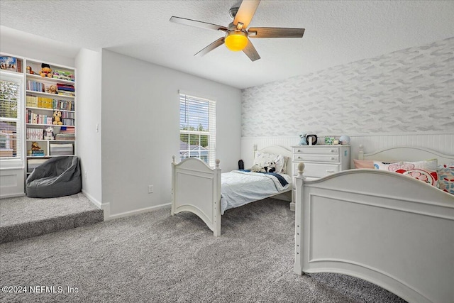 bedroom featuring carpet, a textured ceiling, a ceiling fan, wallpapered walls, and baseboards