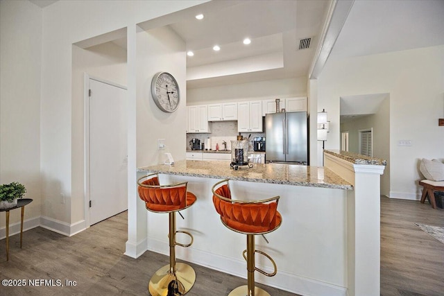 58 Tifton Way N, Ponte Vedra Beach, FL 32082 - kitchen featuring freestanding refrigerator, dark wood-type flooring, light stone countertops, white cabinetry, and a kitchen breakfast bar