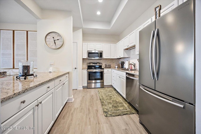 58 Tifton Way N, Ponte Vedra Beach, FL 32082 - kitchen featuring stainless steel appliances, light wood-style floors, white cabinetry, light stone counters, and decorative backsplash