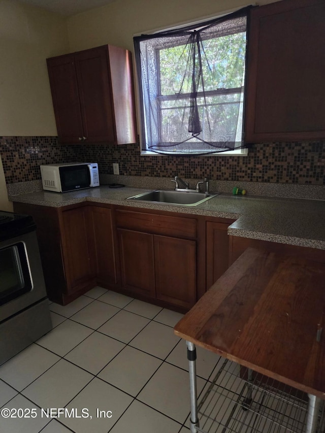 6450 San Juan Ave, Jacksonville, FL 32210 - kitchen featuring white microwave, light tile patterned floors, stove, a sink, and backsplash