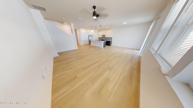 unfurnished living room featuring visible vents, ceiling fan, light wood finished floors, stairway, and recessed lighting