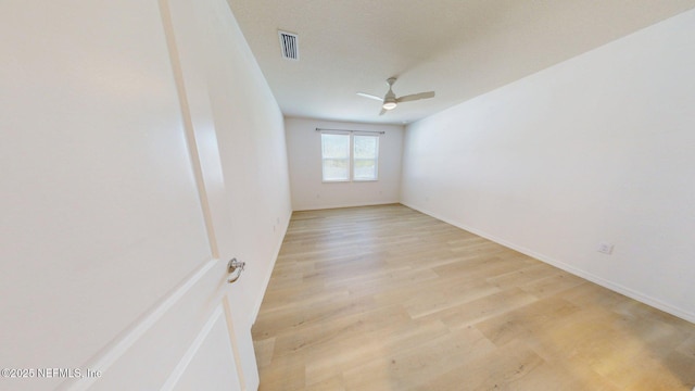 empty room with light wood-type flooring, ceiling fan, baseboards, and visible vents