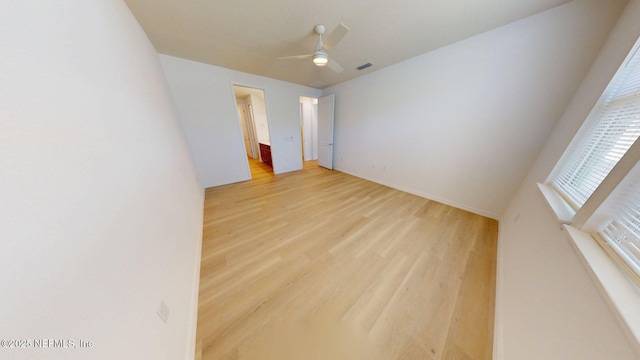 unfurnished room with visible vents, light wood-type flooring, and a ceiling fan