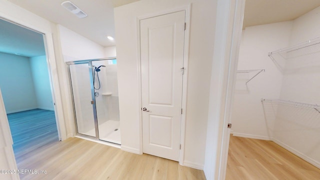 full bath featuring visible vents, baseboards, a spacious closet, wood finished floors, and a stall shower