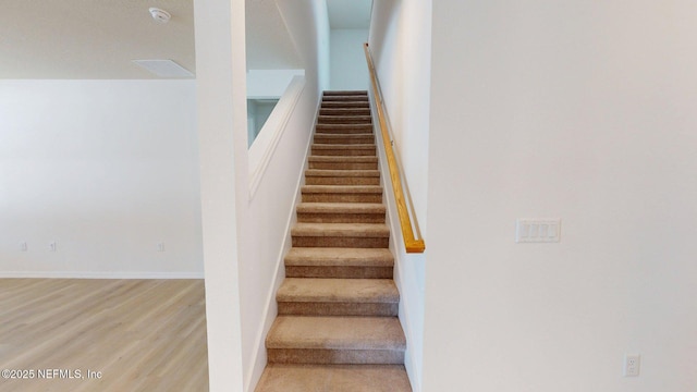 stairs with wood finished floors, baseboards, and visible vents